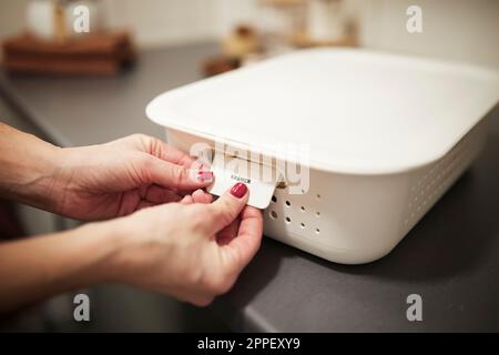 Mains de femme mettant l'étiquette sur le panier Banque D'Images