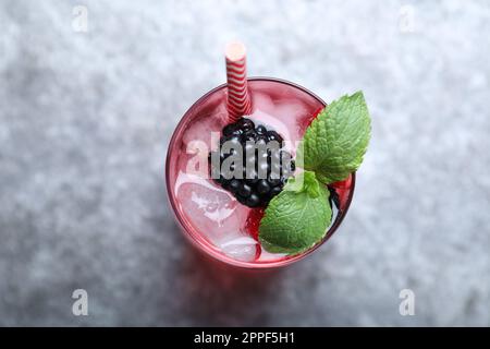 Délicieuse limonade aux fraises avec soda, menthe et mûres sur table grise, vue de dessus. Cocktail d'été frais Banque D'Images