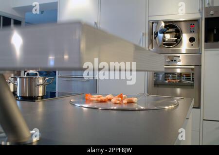 Une casserole en acier avec des crevettes crues sur un comptoir en acier inoxydable dans une cuisine moderne de restaurant sans personnes. Banque D'Images