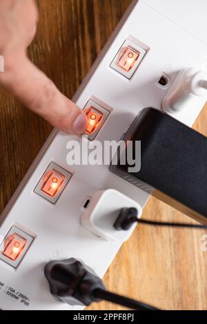 Gros plan a main man allumer l'interrupteur sur la barre d'alimentation. Banque D'Images