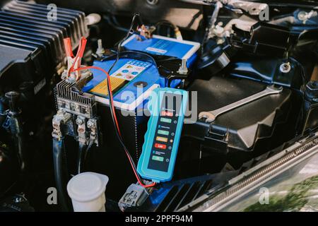 Vérification du niveau de batterie d'une voiture avec le vérificateur de batterie de voiture, concept de réparation de voiture Banque D'Images