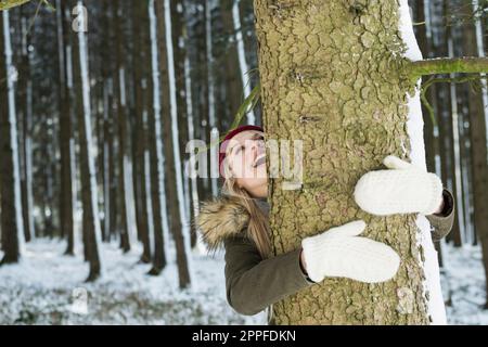 Adolescente embrassant un arbre dans une forêt, Bavière, Allemagne Banque D'Images