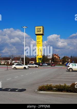 Épicerie Stop and Shop, poteau Stop Shop avec des noms de marque, peint en jaune. Parking devant un grand centre commercial. Sremska Mitrovica, Serbie, 16 mars 2023 Manie du shopping et consumérisme. Banque D'Images