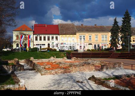 Sremska Mitrovica, Serbie, 16 mars 2023 place historique Zitni trg. Anciens bâtiments multicolores et fouilles de l'époque romaine. Patrimoine culturel. Ciel spectaculaire. Fouilles de chambres romaines. Banque D'Images