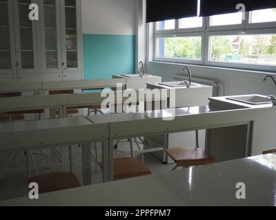 Salle de chimie dans une nouvelle école moderne. Beau mobilier blanc avec éviers et lavabos. Grandes fenêtres avec rideaux occultants ou stores. Salle de classe vide. Mobilier et équipement scolaire Banque D'Images