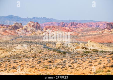 Route sinueuse dans le désert avec des montagnes rougeâtres dans le bkgrnd Banque D'Images