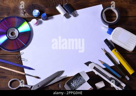 Une école ou un bureau a encore une vie avec une feuille blanche de papier vierge et beaucoup de fournitures de bureau. Les fournitures scolaires se trouvent sur un fond de bois brun. Placer pour le texte Banque D'Images