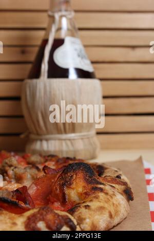 Pizza fraîche sur une table en bois au restaurant avec une bouteille de Chianti en arrière-plan Banque D'Images