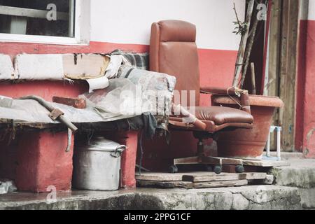 une vieille chaise cassée dehors et d'autres déchets. Banque D'Images