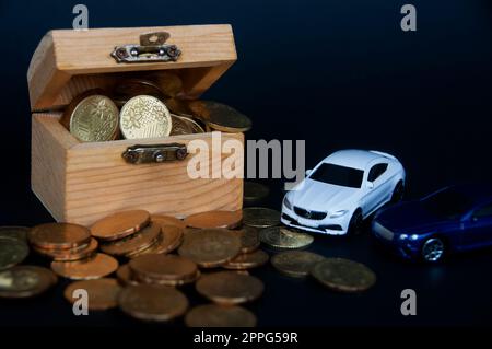 Kuala Lumpur, Malaisie - juillet 2022 : voiture miniature de Mercedes AMG et Bentley Continental GT avec des pièces d'or et un coffre au Trésor sur fond noir. Banque D'Images