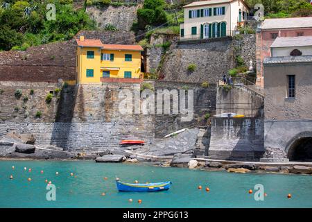 Vue sur la baie d'eau avec des bateaux amarrés et des maisons colorées typiques dans un petit village, Riviera di Levante, Vernazza, Cinque Terre, Italie Banque D'Images