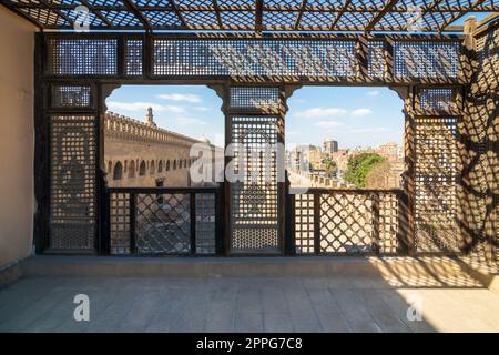 Passage entourant la mosquée Ibn Tulun encadrée par une fenêtre en bois, Mashrabiya, le Caire, Egypte Banque D'Images