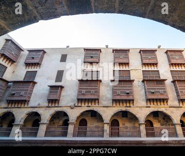 Façade du caravansaire de Bazaraa encadrée par une arche de pierre, avec arcades voûtées et fenêtres en oriel en bois, le Caire, Egypte Banque D'Images