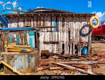 Shabby petit bâtiment parmi beaucoup de conseil avec vieil économiseur de vie orange sur le bord du toit Banque D'Images