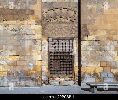 Fenêtre en bois grunge avec grille en fer décorée sur un mur en briques de pierre et un banc de jardin en marbre Banque D'Images