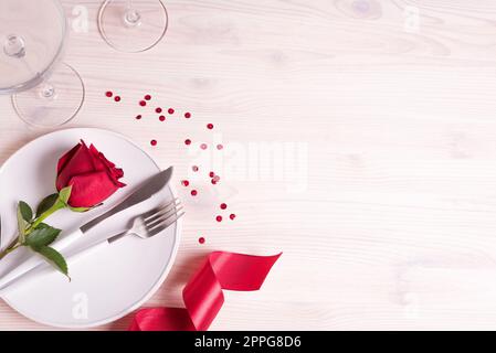 Décor de table datant de la Saint-Valentin, verres à champagne et roses rouges sur fond blanc, vue sur le dessus, espace copie. Menu dîner romantique pour la Saint-Valentin concep Banque D'Images