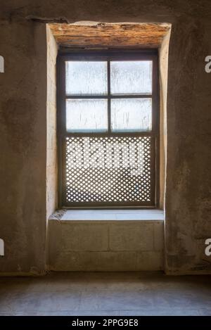 Simple fenêtre ornée en bois grunge entrelacé - Mashrabiya - dans le mur de pierre au bâtiment abandonné Banque D'Images