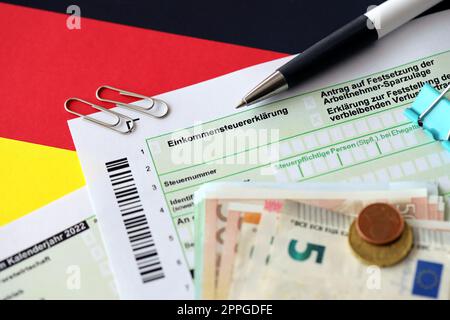 Formulaire de déclaration d'impôt sur le revenu allemand avec stylo et billets de monnaie européens se trouve sur le drapeau de près. Les contribuables allemands utilisent l'euro pour payer leurs impôts Banque D'Images