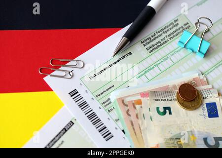 Formulaire de déclaration d'impôt sur le revenu allemand avec stylo et billets de monnaie européens se trouve sur le drapeau de près. Les contribuables allemands utilisent l'euro pour payer leurs impôts Banque D'Images