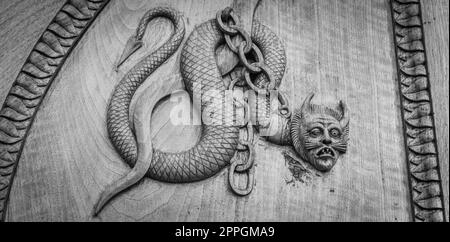 Symbole serpent de diable. Créature magique fantaisie sur une vieille porte, abbaye du 12th siècle en Italie. Banque D'Images