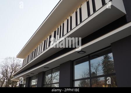 Bâtiment moderne. Thuja avec une couronne cisaillée en forme. Aménagement paysager moderne. Belle décoration du jardin, pelouse, territoire de la maison. Mur gris avec décor rayé, grandes fenêtres vitrées. Banque D'Images