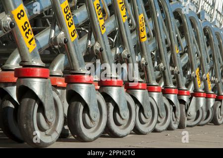 Vue oblique des roues d'une rangée de chariots poussés ensemble en attendant les clients dans un supermarché Banque D'Images