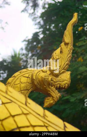 Sculpture dorée d'un serpent naga, créature mythique protectrice, à l'entrée d'un temple bouddhiste à Luang Prabang, au Laos. Banque D'Images