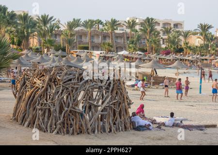 cabane créative faite de bois de grève près de nombreux parasols de plage à la mer Banque D'Images