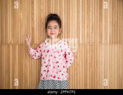 Portrait de la petite fille heureuse , arrière-plan en bois, montrer trois doigts Banque D'Images