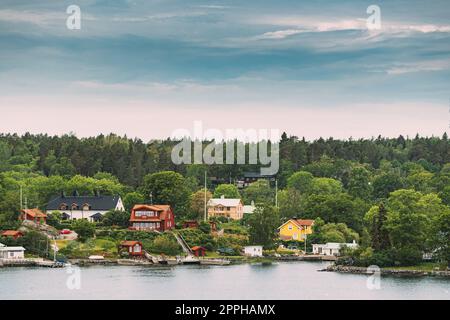 Suède. Magnifique cabane en bois rouge suédois sur la côte des îles Rocheuses en été Sunny soir. Paysage de lac ou de rivière Banque D'Images