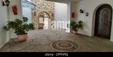 Grand intérieur d'entrée de maison ancienne avec plantes vertes et murs de briques. Banque D'Images
