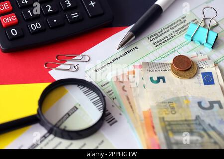 Formulaire de déclaration d'impôt sur le revenu allemand avec stylo et billets de monnaie européens se trouve sur le drapeau de près. Les contribuables allemands utilisent l'euro pour payer leurs impôts Banque D'Images