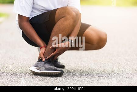 sport coureur homme utiliser les mains joint tenir la douleur de jambe parce que de la cheville tordue brisée pendant la course Banque D'Images