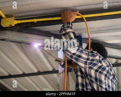 Un soudeur travaille sur un châssis en acier. Sur le chantier. Banque D'Images
