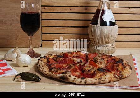 Pizza fraîche sur une table en bois au restaurant avec une bouteille de Chianti en arrière-plan Banque D'Images