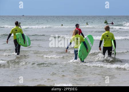 Vacanciers prenant part à une leçon de surf avec un instructeur à Fistral Beach à Newquay, en Cornouailles, au Royaume-Uni. Banque D'Images