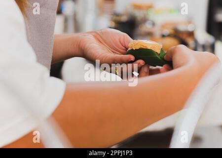 Femme vendeur préparant du riz collant avec de la crème anglaise enveloppée dans un congé de banane. Banque D'Images