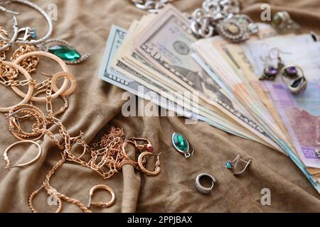 Bouquet de bijoux volés et de l'argent sur tissu d'uniforme militaire. Pillage par des soldats russes dans les villes ukrainiennes lors de l'attaque russe sur l'Ukraine. Maraudeurs et pilleurs Banque D'Images