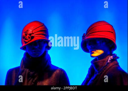 Deux mannequins habillés de chapeaux rouges sur fond bleu Banque D'Images