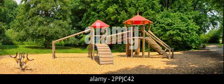 Un château d'escalade en bois avec des tours, des palisades, des toboggans, des cordes et des barres d'équilibrage sur une aire de jeux déserte Banque D'Images