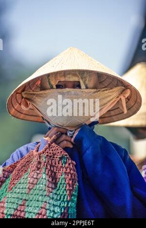 Diapositive numérisée d'une photographie en couleur historique d'une femme non reconnaissable portant un chapeau de riz et un masque à poussière au Vietnam Banque D'Images