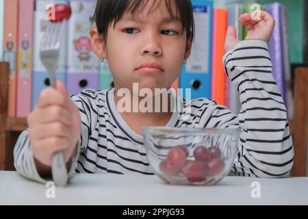 Les enfants n'aiment pas manger des fruits. Mignonne jeune fille asiatique refusant de manger des fruits sains. Nutrition et habitudes alimentaires saines pour les enfants. Banque D'Images