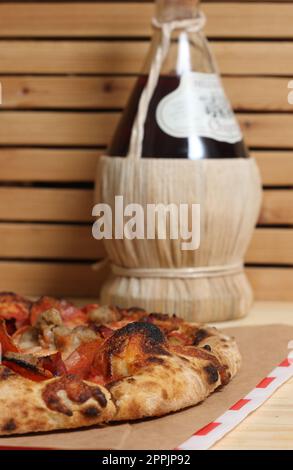 Pizza fraîche sur une table en bois au restaurant avec une bouteille de Chianti en arrière-plan Banque D'Images