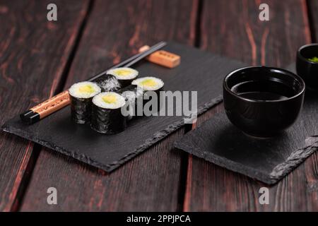 Un petit sushi Maki accompagné d'avocat et de baguettes. Menu sushi. Cuisine japonaise. Banque D'Images