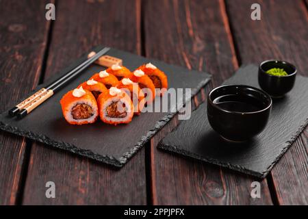 Petit pain de sushi au thon, oignon dans la pâte et tobiko caviar servi sur tableau noir - cuisine japonaise Banque D'Images