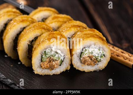 Rouleau de sushi avec thon fumé avec concombre et fromage gros plan. Ensemble traditionnel délicieux de rouleaux de sushi frais. Menu sushi. Restaurant de cuisine japonaise. Cuisine asiatique Banque D'Images