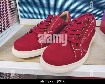 Baskets rouges ou baskets en daim naturel sur une étagère de magasin. Semelle flexible blanche et lacets rouges. Magasin de chaussures. Chaussures tendance confortables pour jeunes. Concept le plus récent. Les meilleures chaussures de course rouges. Banque D'Images