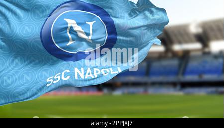 Drapeau de la SSC Napoli agitant avec le stade Diego Armando Maradona flou en arrière-plan Banque D'Images