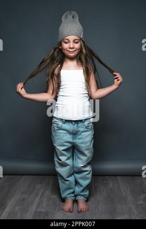 Petite fille modèle professionnellement posant dans le studio en jeans et un T-shirt blanc. Tests de modèles Banque D'Images