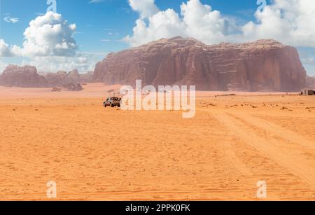 Sable orange et falaises du désert de Wadi Rum avec voiture touristique en arrière-plan, Jordanie Banque D'Images